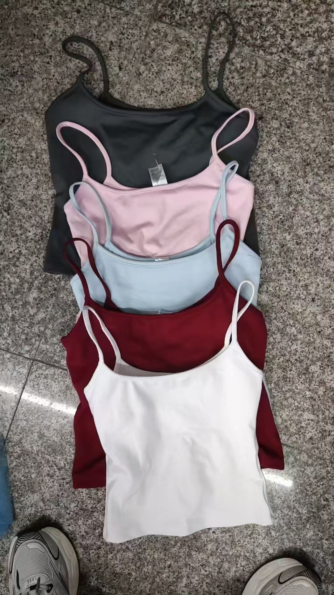 Women's ribbed tank tops in multiple colors, including pink, white, blue, black, and red, stacked and laid flat.