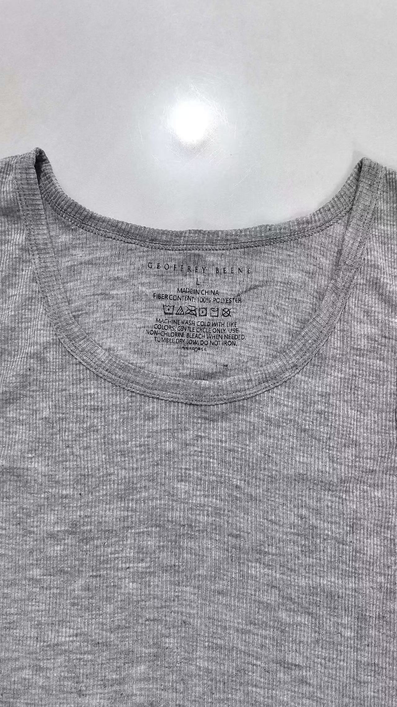 Close-up of grey men's tank top showing fabric weave texture and collar seam.