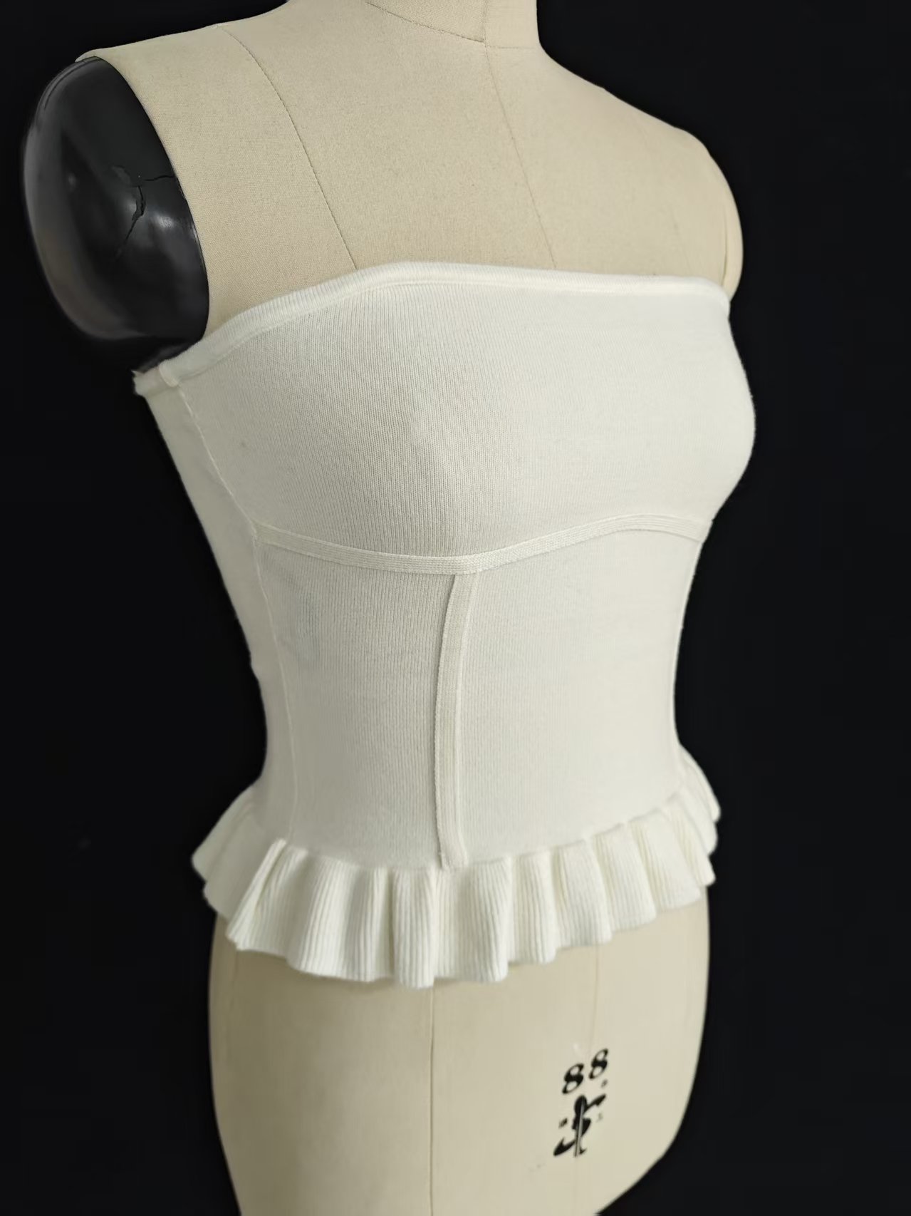 Side view detail of white women's strapless tube top on a mannequin showcasing fit and side seam construction.