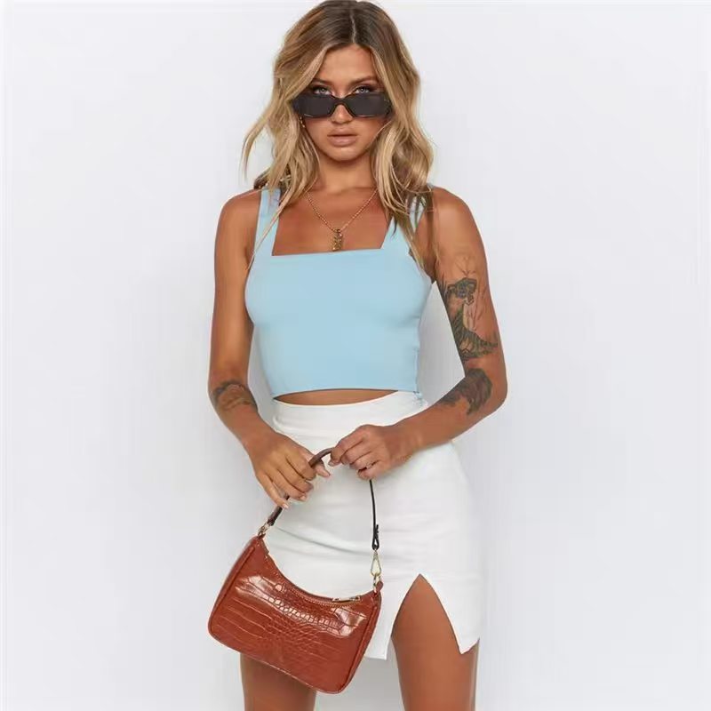 Female model wearing a beige ribbed scoop neck crop top with light-colored shorts.
