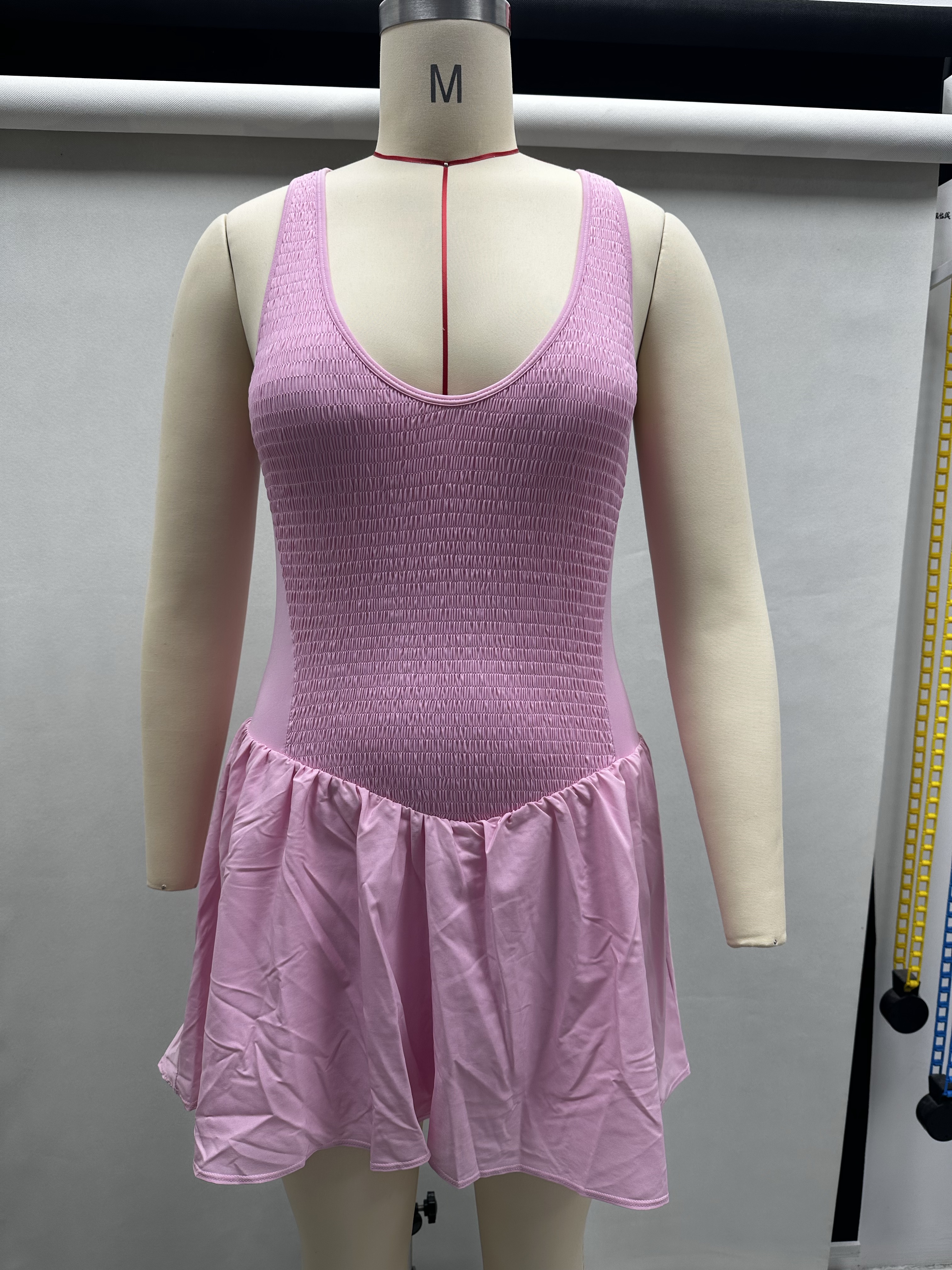 Front view of pink women's athletic tennis dress displayed on a torso mannequin showing the scoop neckline and waist line.