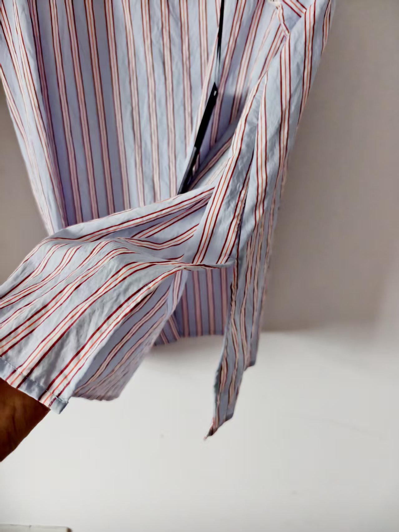 Detail view of blue and red striped women's V-neck dress highlighting the front waist wrap tie construction.