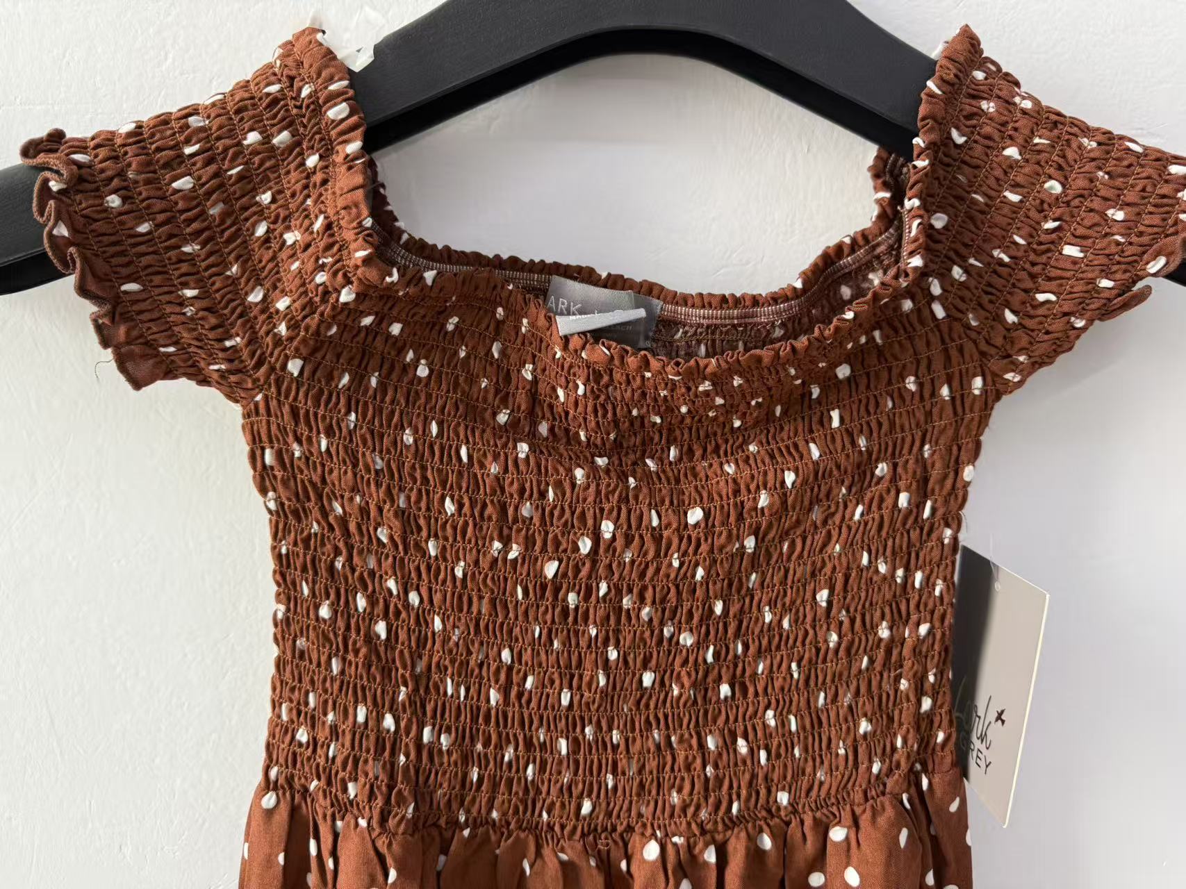 Close-up of cocoa brown women's short-sleeve dress with white polka dots, highlighting the elastic waist and neckline detail.