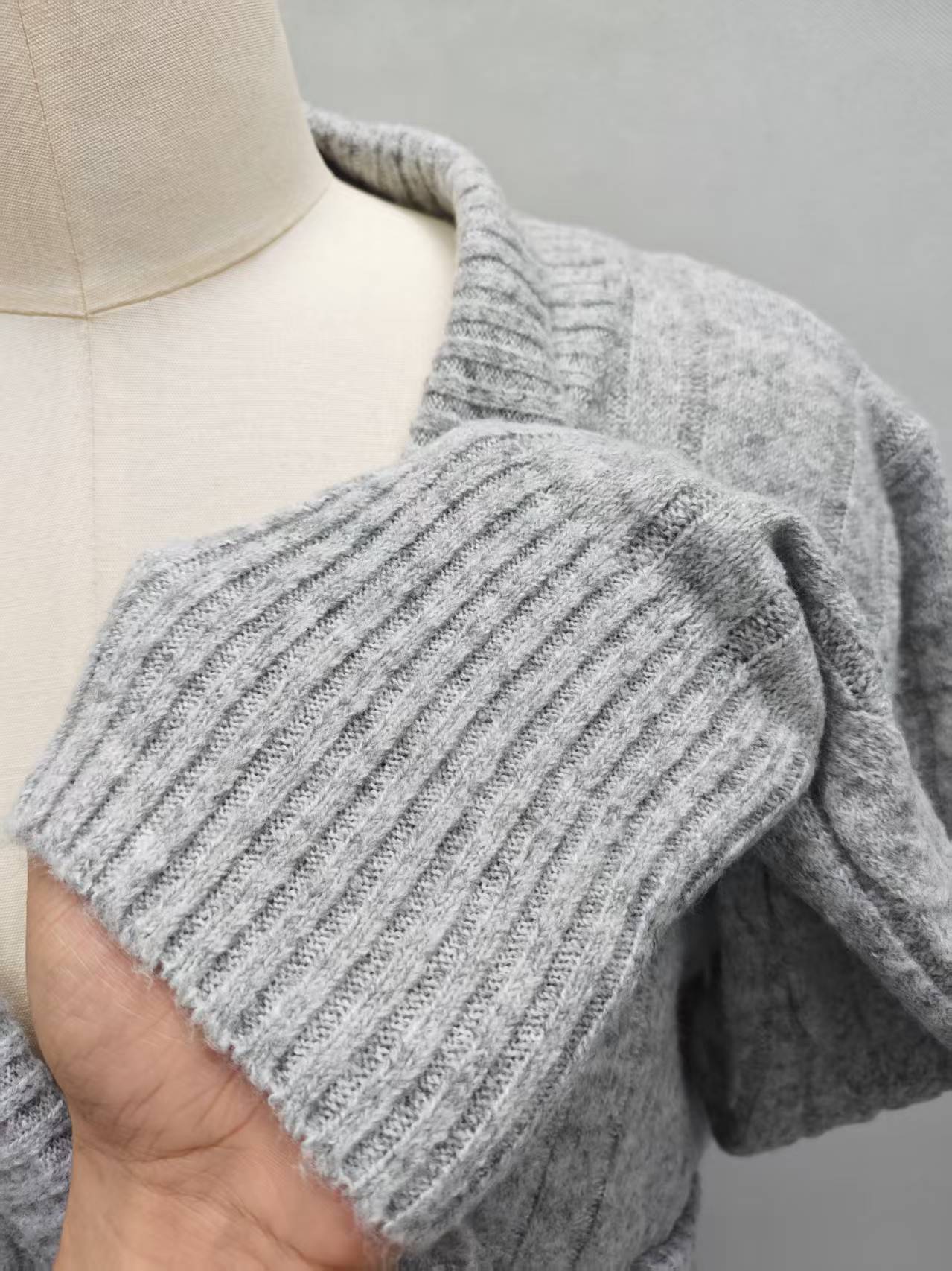 Close-up shot of the grey women's cardigan sweater highlighting the knit fabric texture, front opening, and collar seam.