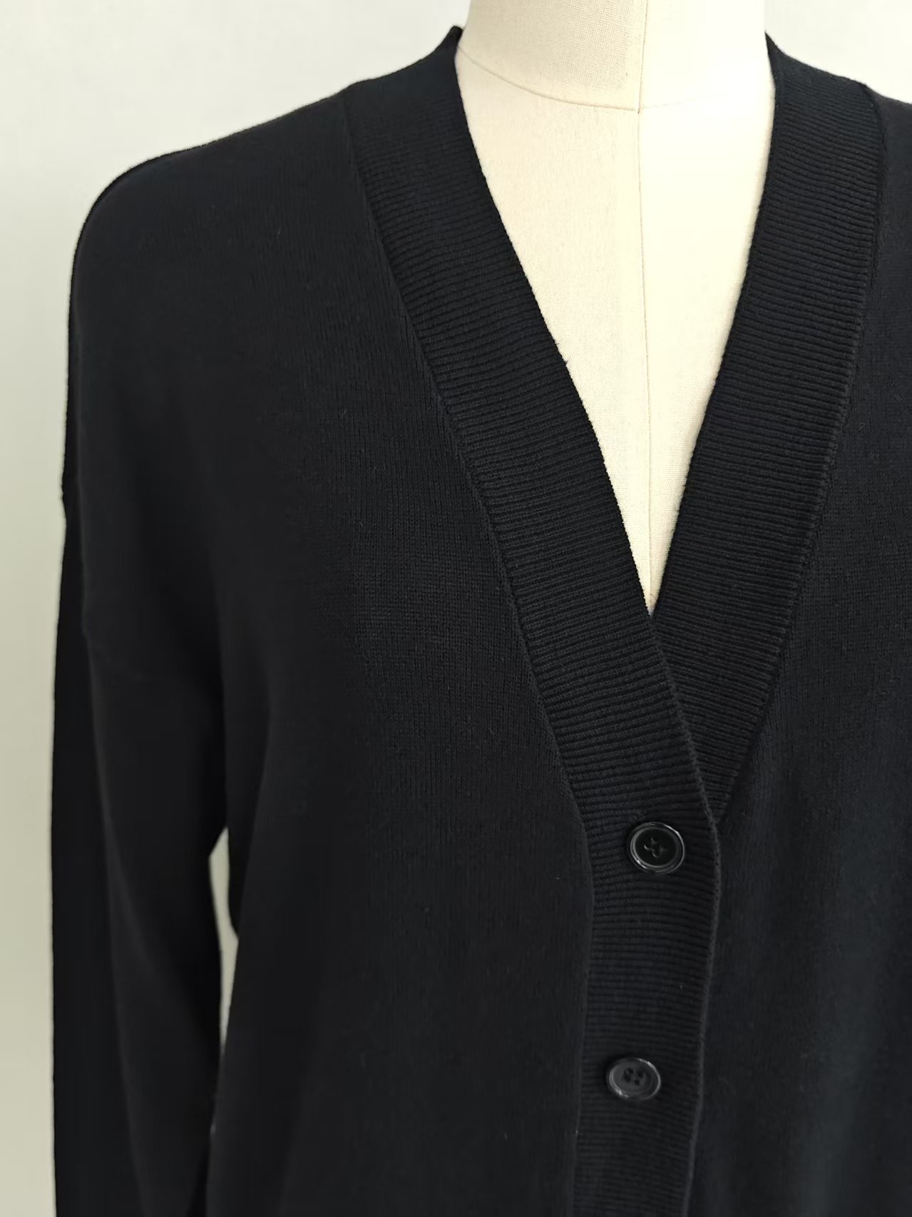 Close-up detail of v-neck collar and buttons on black cardigan