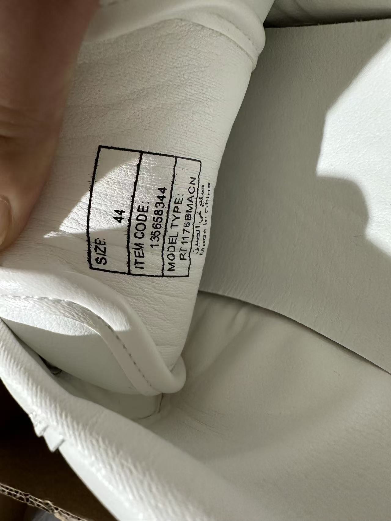 Close-up detail of inner label on men's white shoes