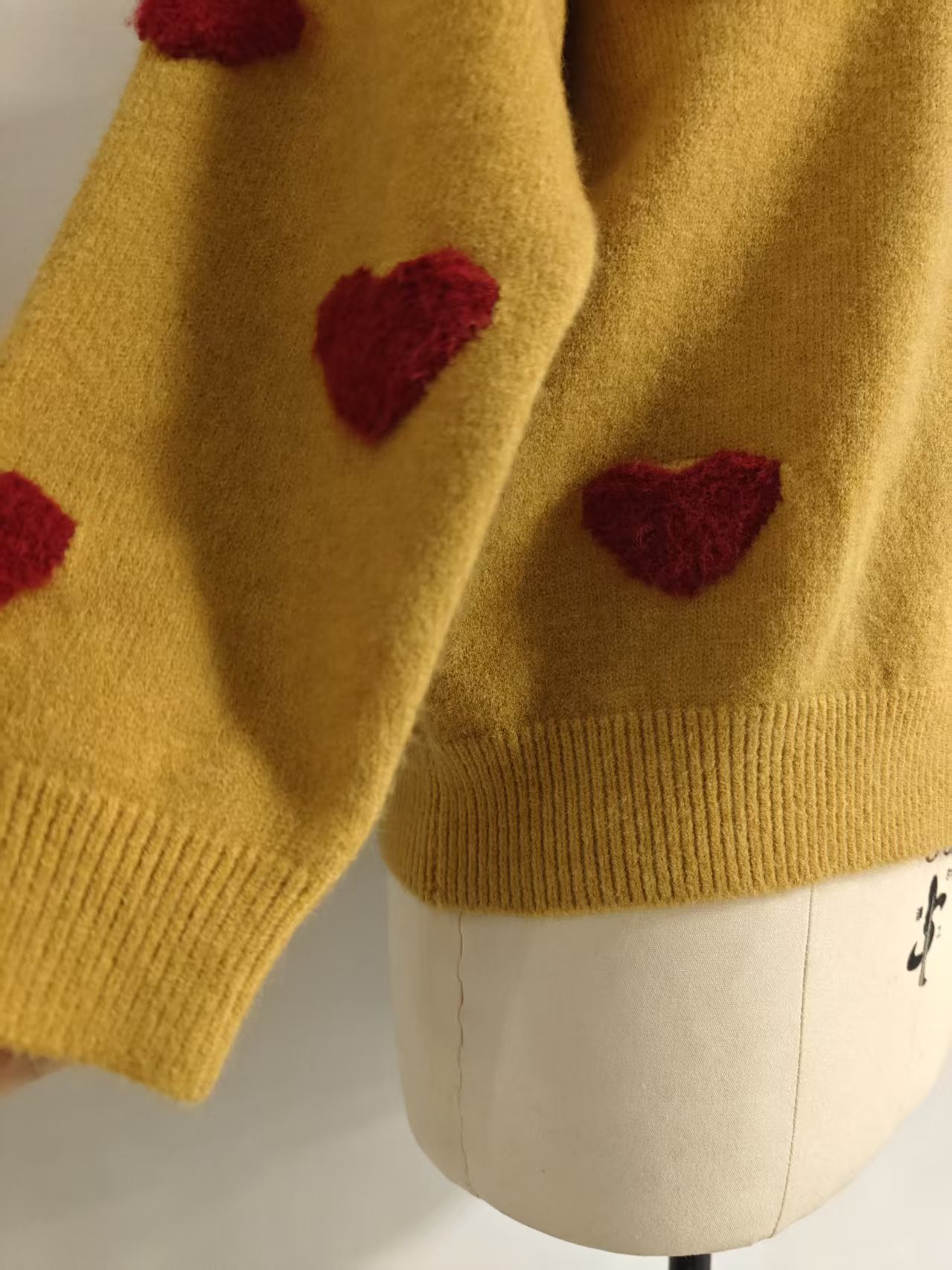 Side view of women's mustard heart patterned knit sweater