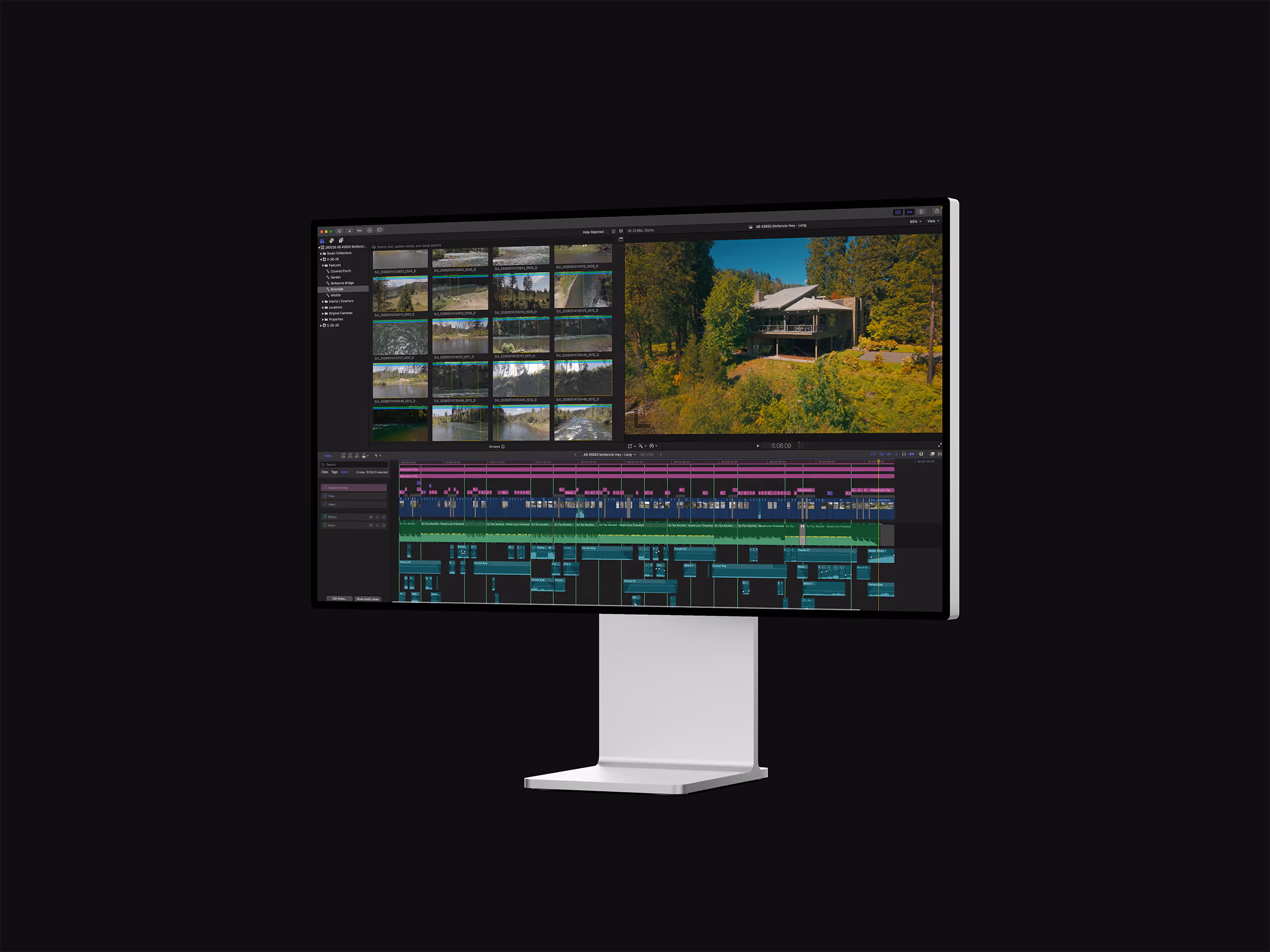 Computer monitor displaying video editing software with clips, timeline, and a house in a forest scene.