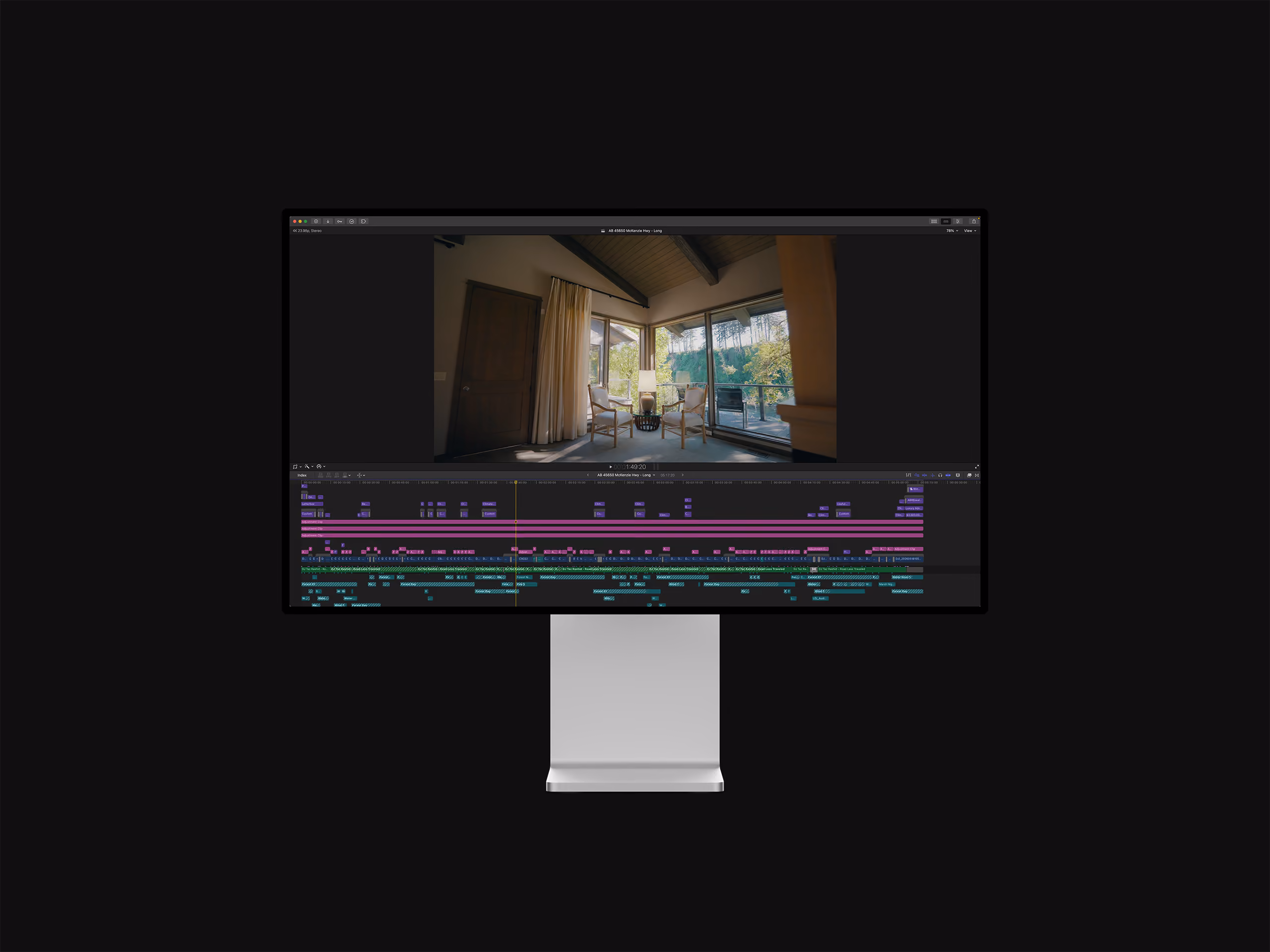 Computer monitor displaying a video editing timeline and preview of a room with chairs and a view outside.