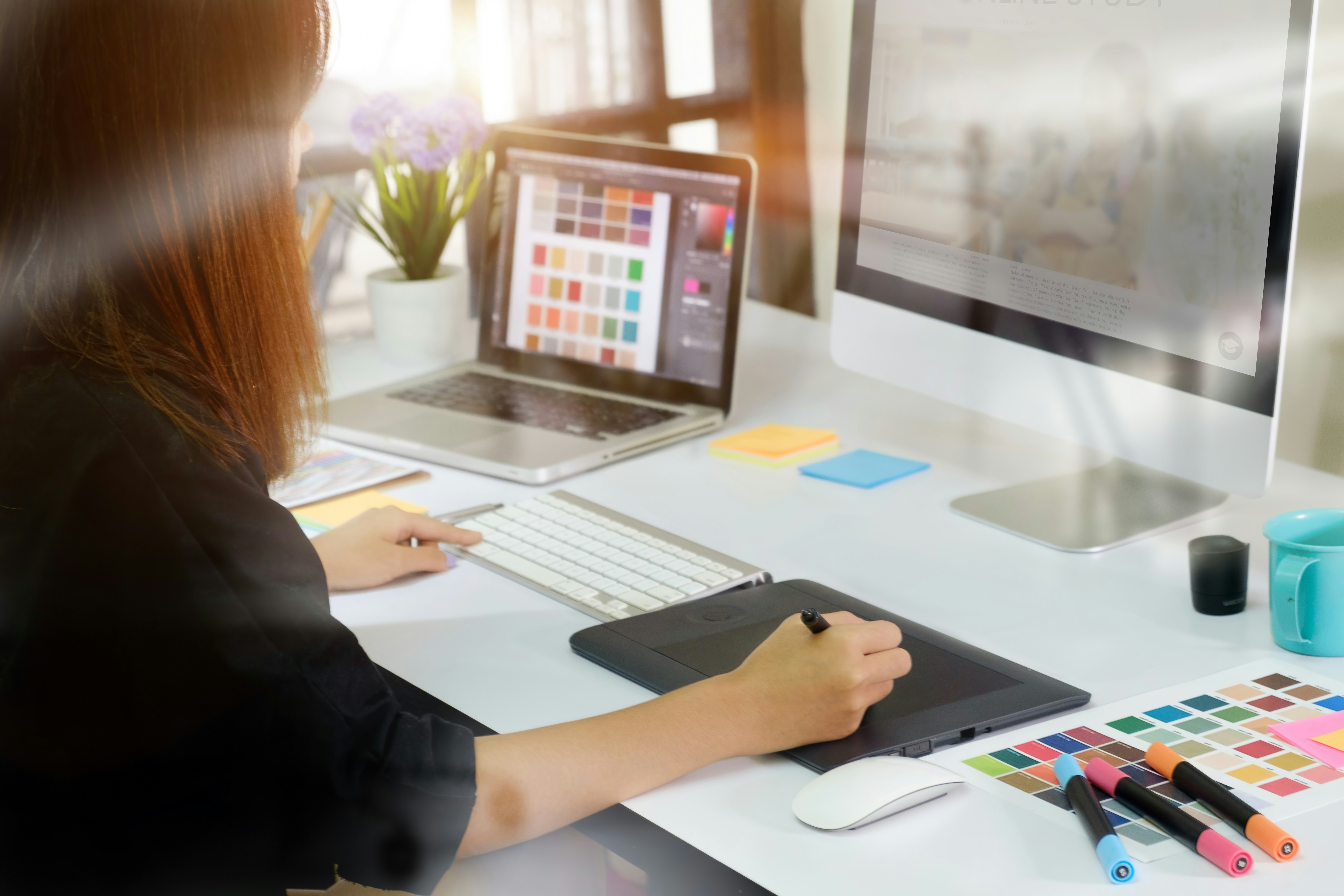Designer reviewing a colour palette on a monitor with a drawing tablet