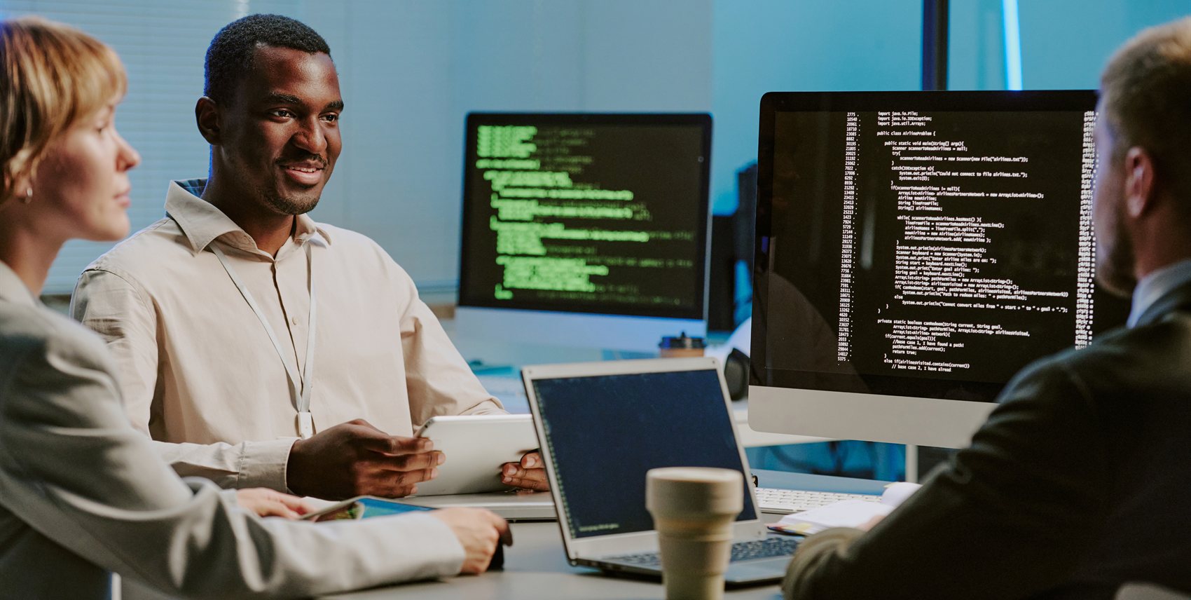 Engineers discussing code on large monitors in an office