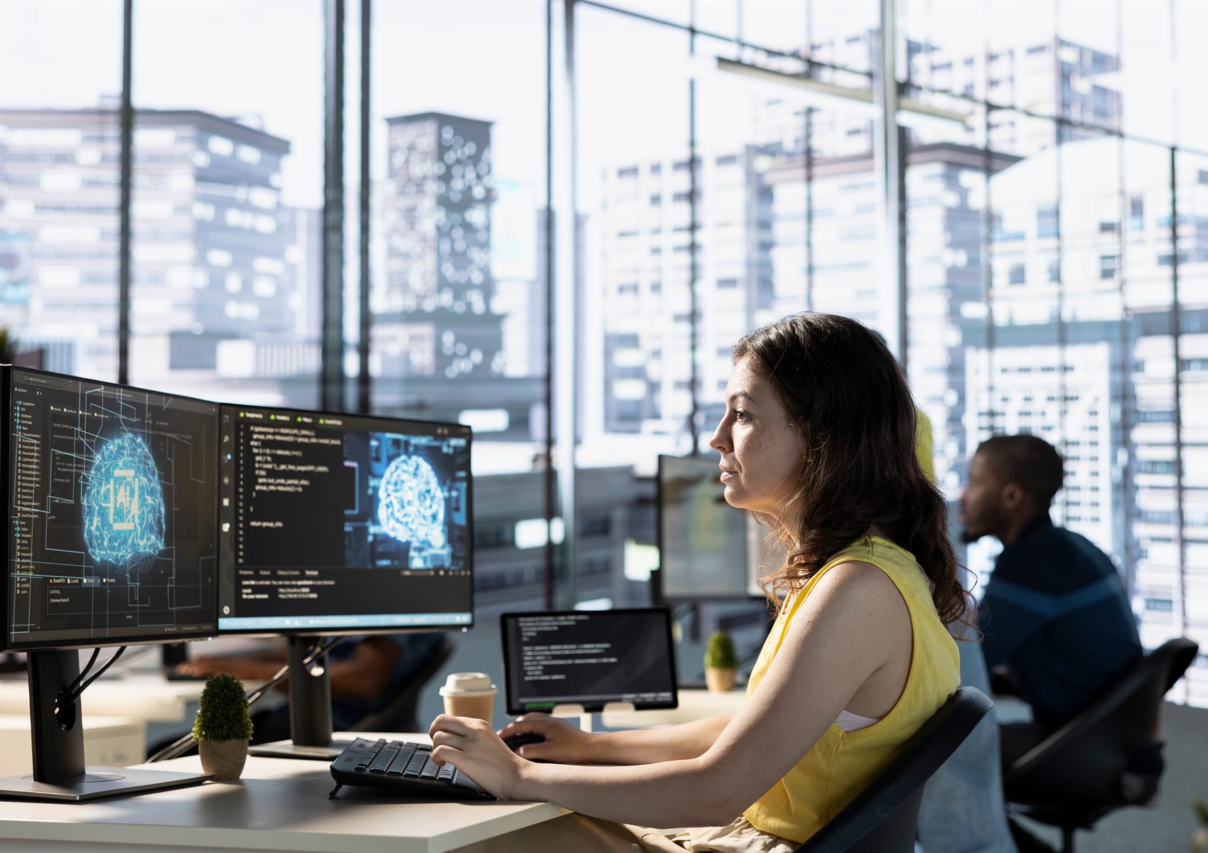 A data scientist reviewing AI model visualisations on dual monitors in a bright open-plan office