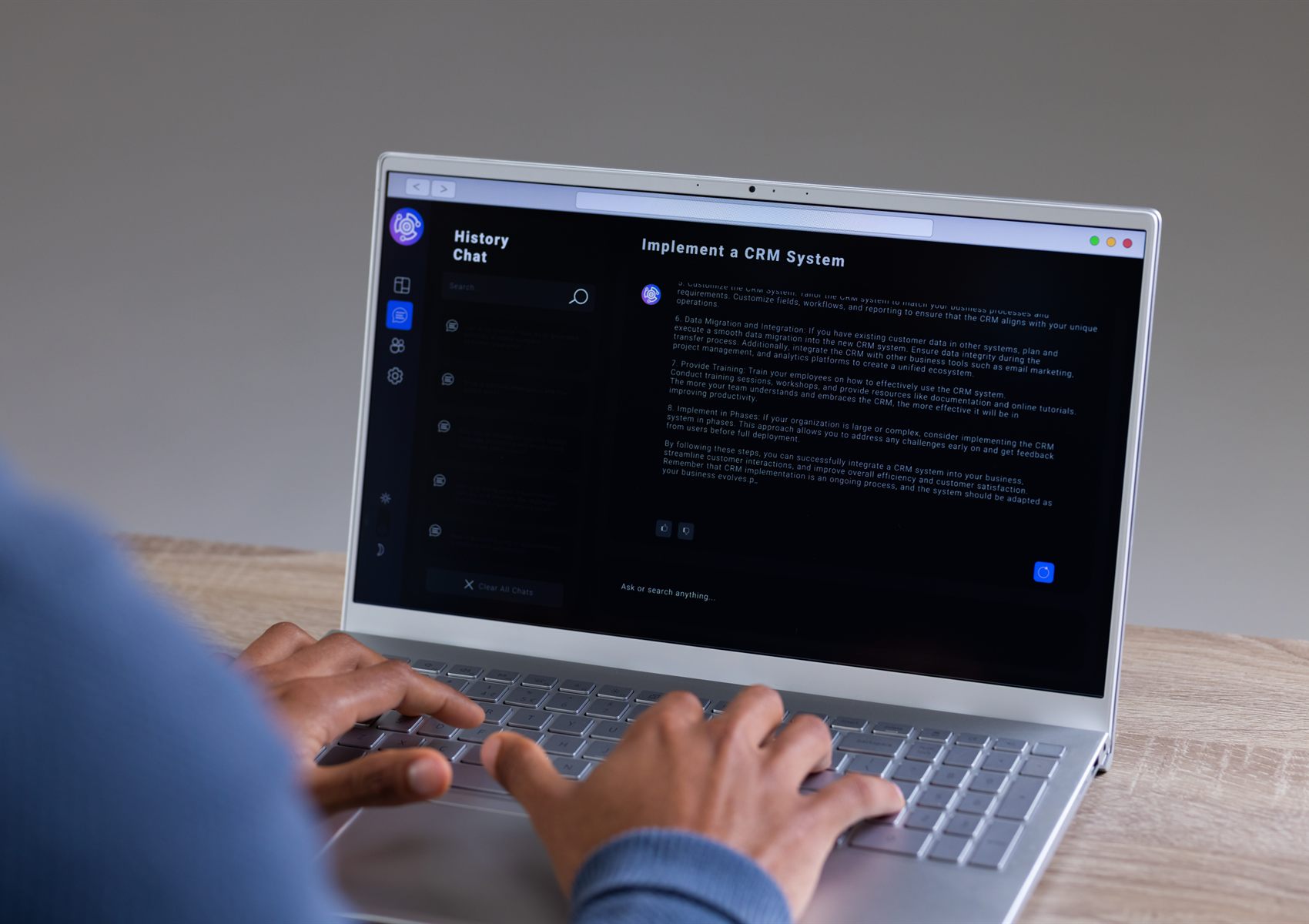 A person typing on a laptop showing an AI assistant planning a CRM system implementation