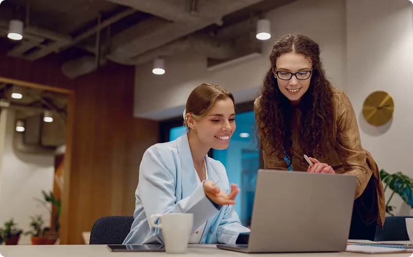 Two colleagues reviewing analysis together on a laptop in a warmly lit office