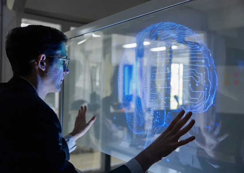 Engineer interacting with a holographic AI brain on a glass display