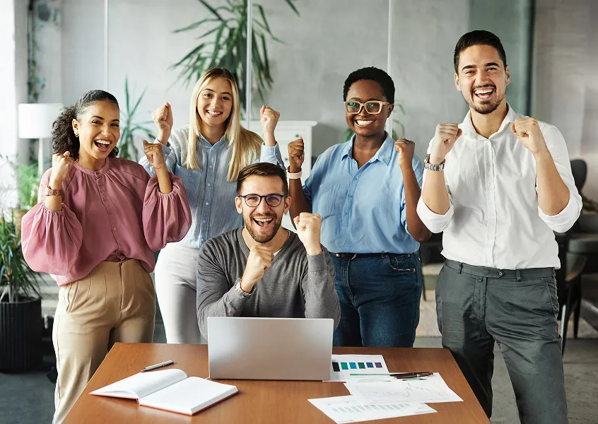 Team celebrating a success together around an office desk