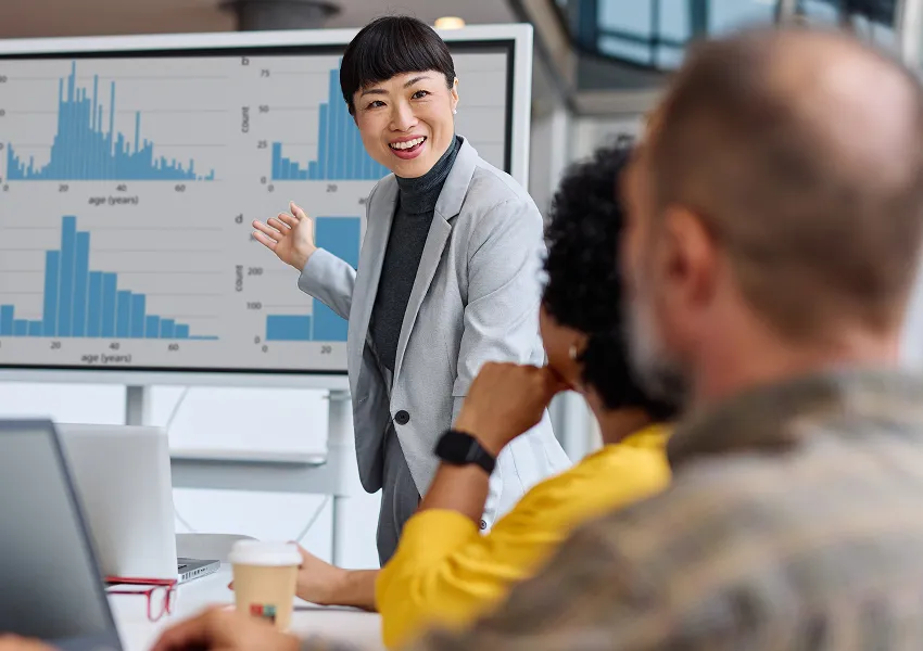 Data professional presenting analytics charts to a team in a modern office.