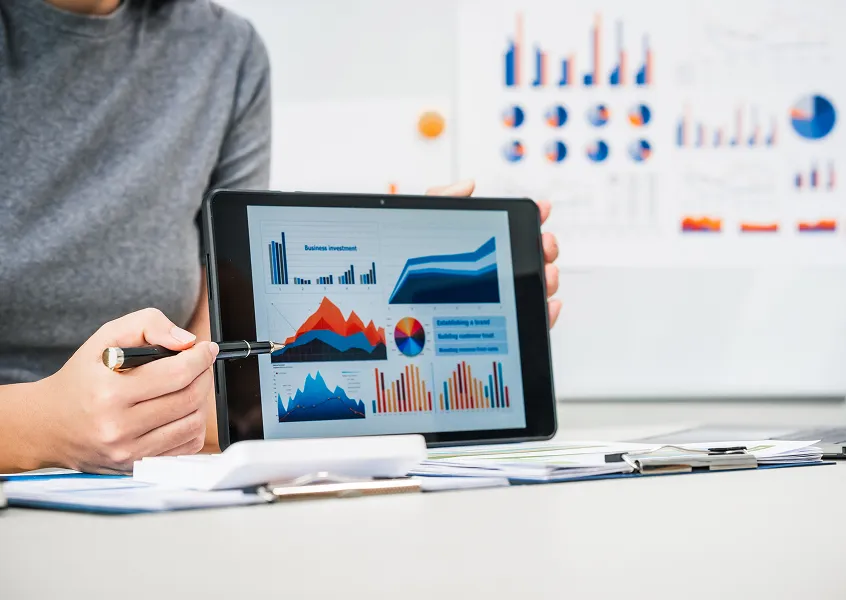 Person pointing a pen at business analytics charts on a tablet