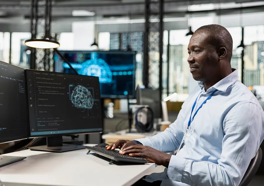 Technology professional working at multiple monitors displaying AI and automation interfaces