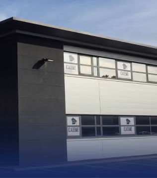 Façade d'un bâtiment moderne gris et blanc aux fenêtres marquées Icademie