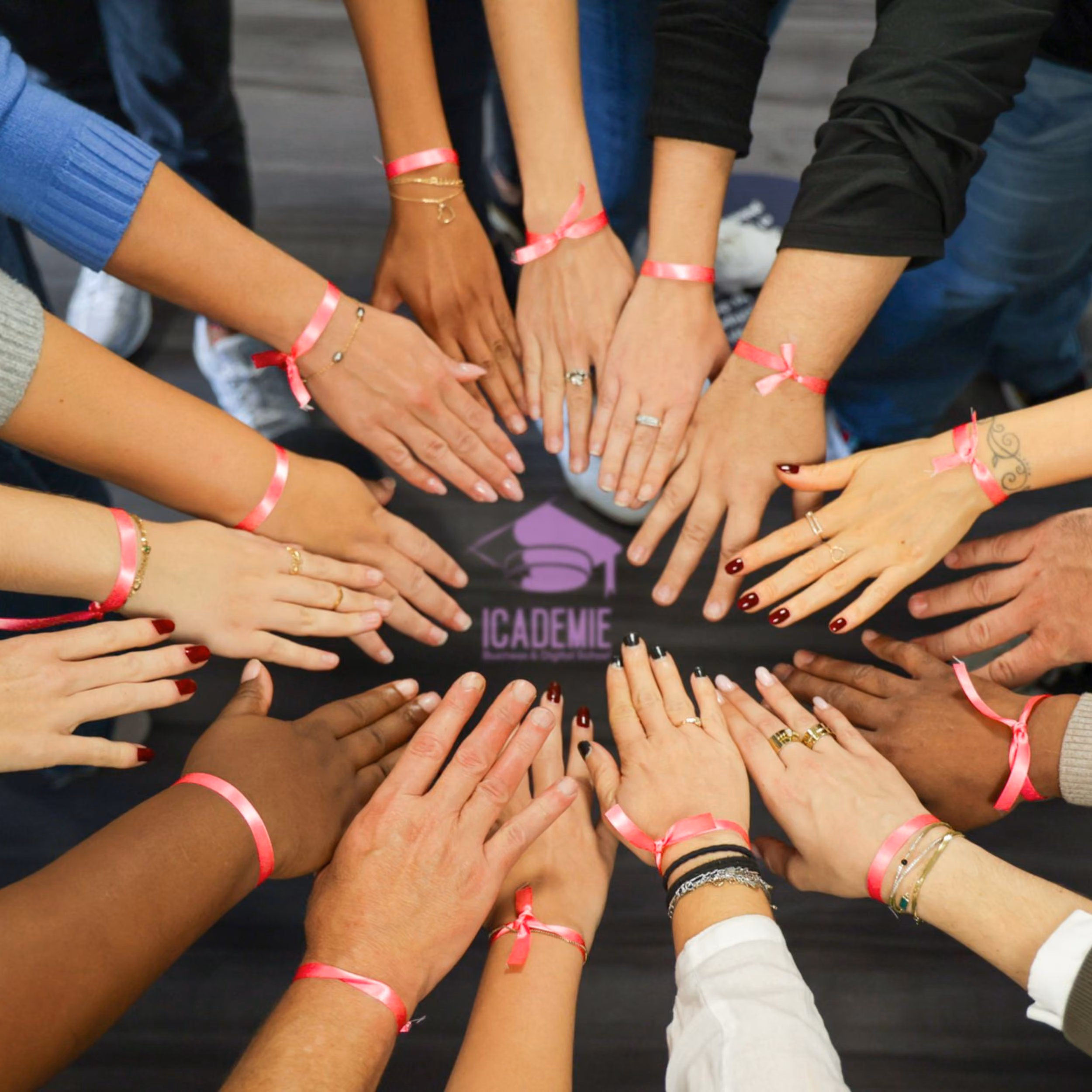 Des mains de personnes diverses formant un cercle, chacune porte un bracelet rose, symbolisant l'unité et la solidarité.