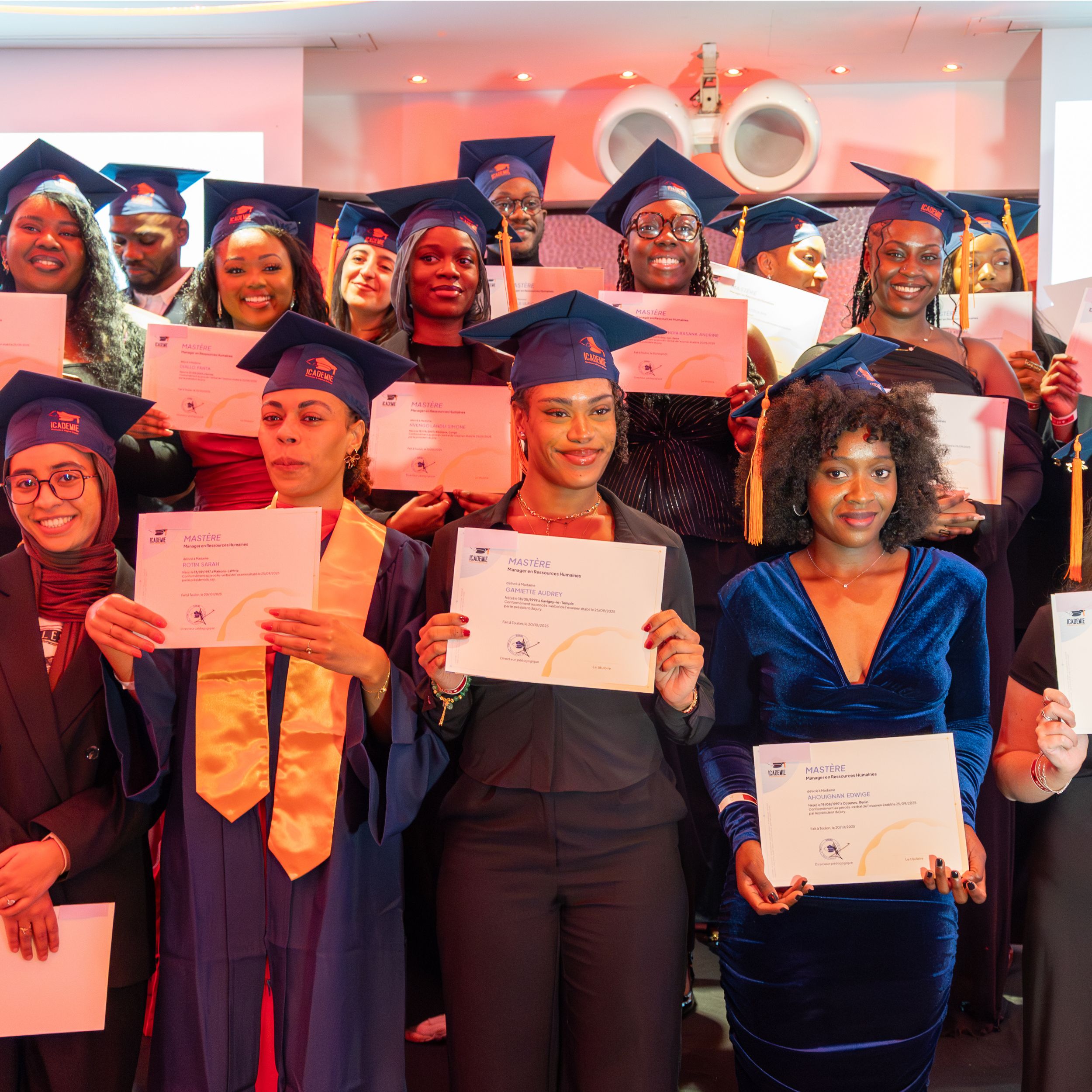 Groupe de diplômées en toque et robe brandissant leurs diplômes