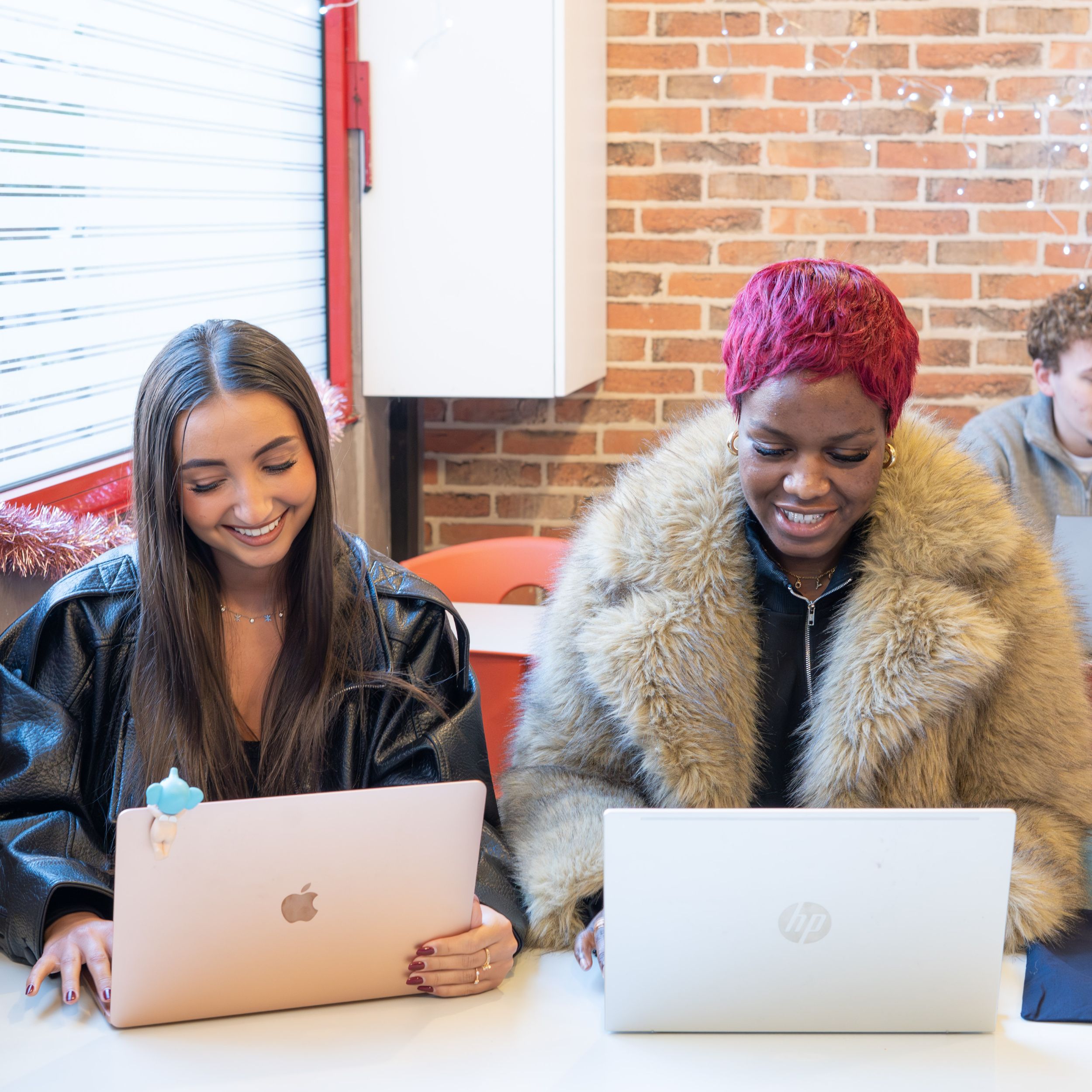 Deux étudiantes souriantes travaillant sur leurs ordinateurs portables
