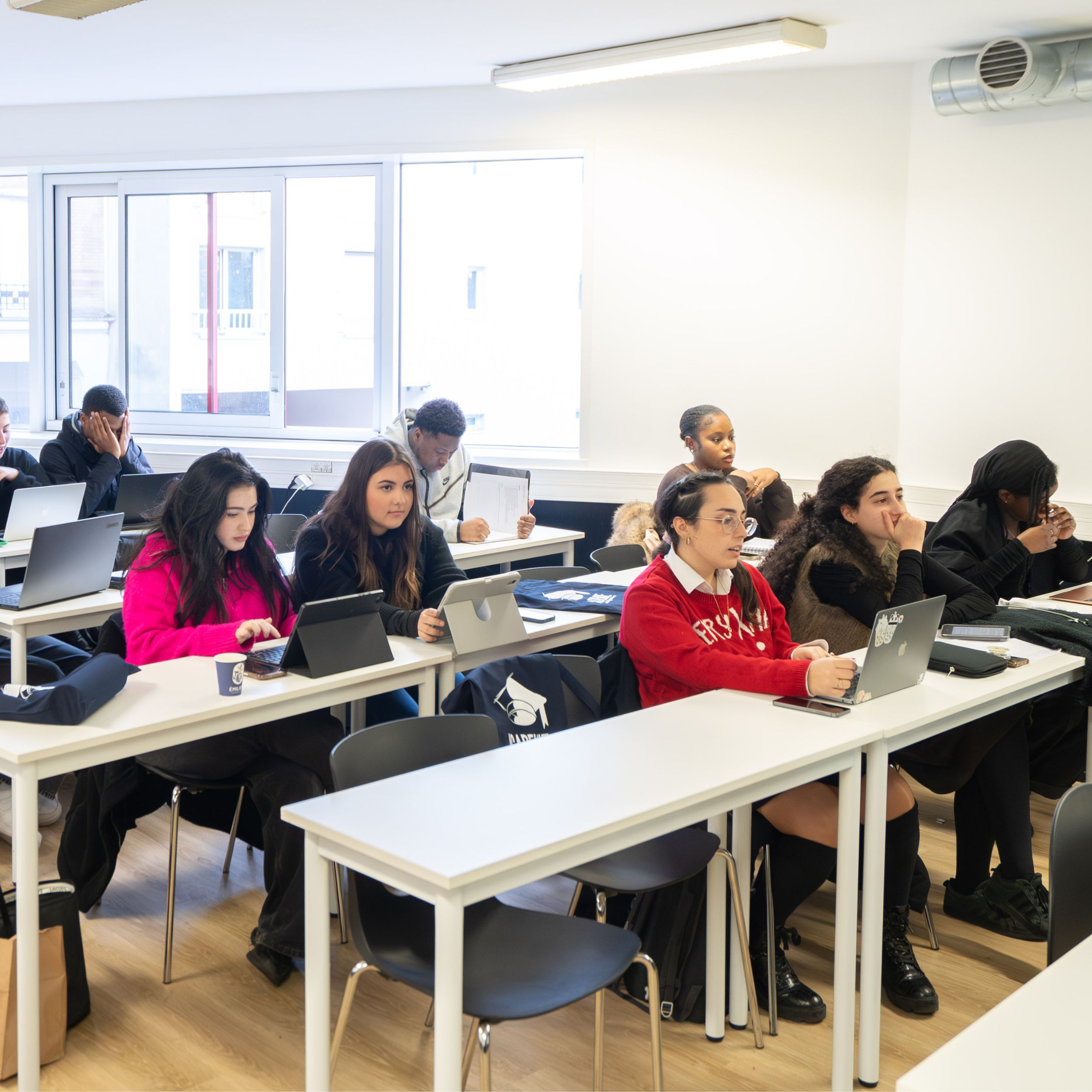 Étudiants en cours sur leurs ordinateurs portables dans une salle de classe lumineuse