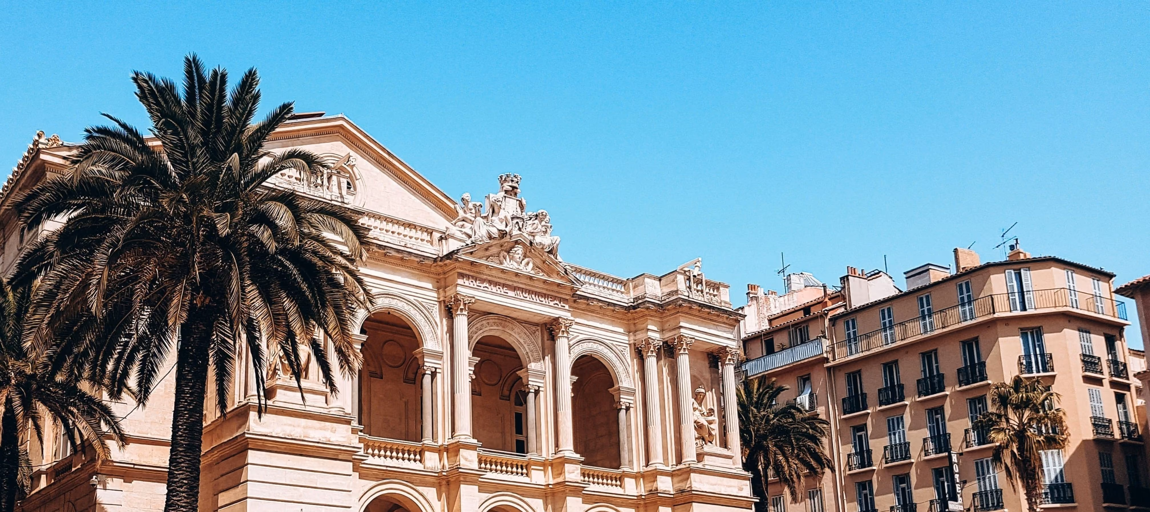 Façade de l'opéra de Toulon bordée de palmiers