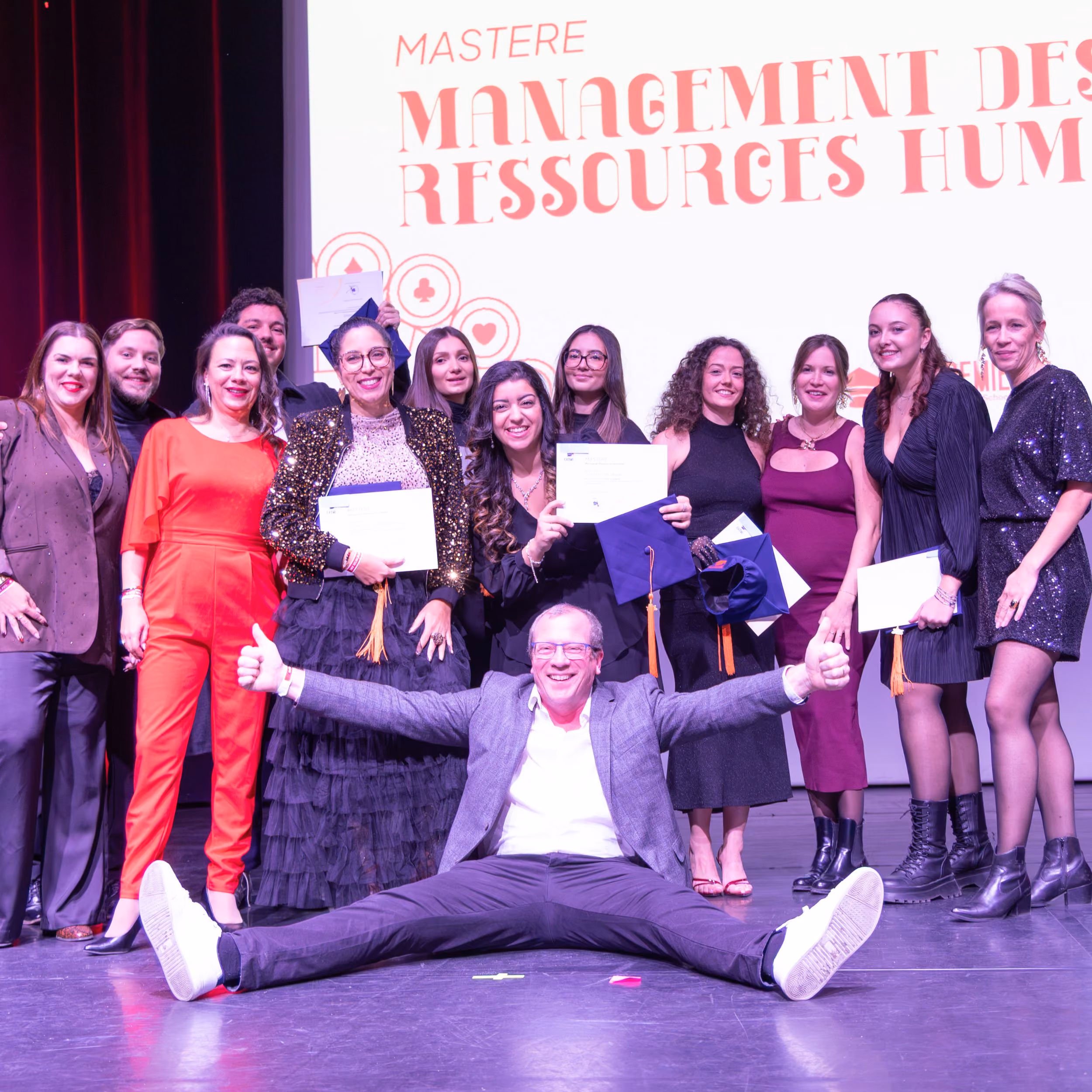 Promotion du Mastère Management des ressources humaines posant sur scène avec ses diplômes