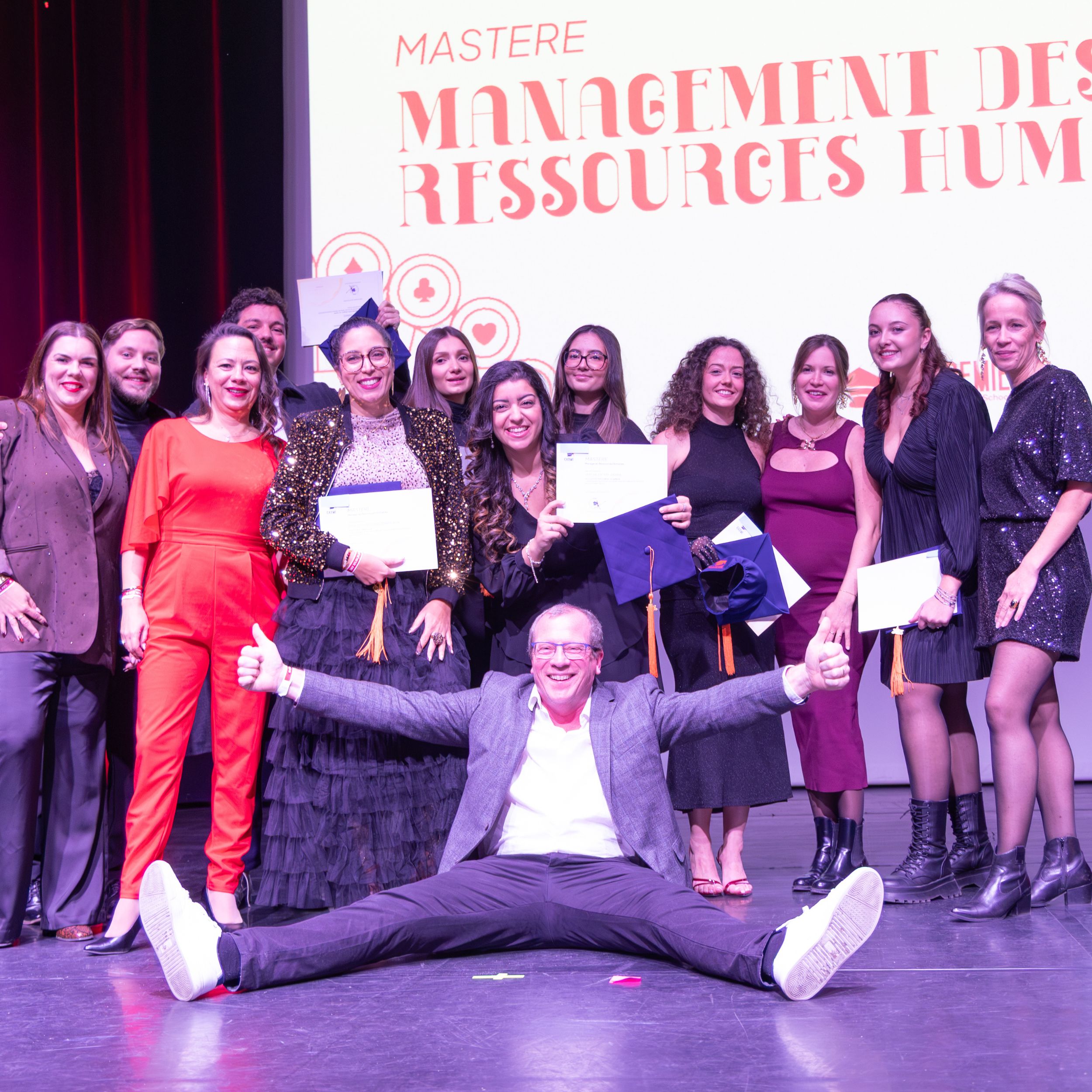 Promotion du Mastère Management des ressources humaines posant sur scène avec ses diplômes