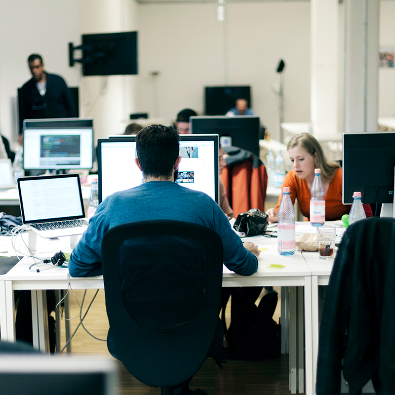 Open space avec des employés travaillant sur plusieurs écrans d'ordinateur