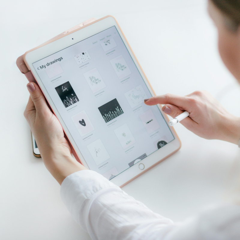 Mains parcourant des maquettes d'interface sur une tablette avec un stylet