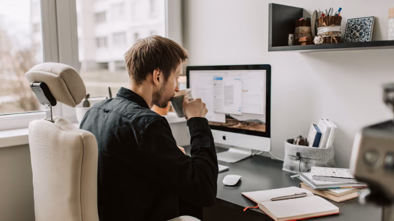 Homme buvant un café devant son ordinateur dans un bureau à domicile