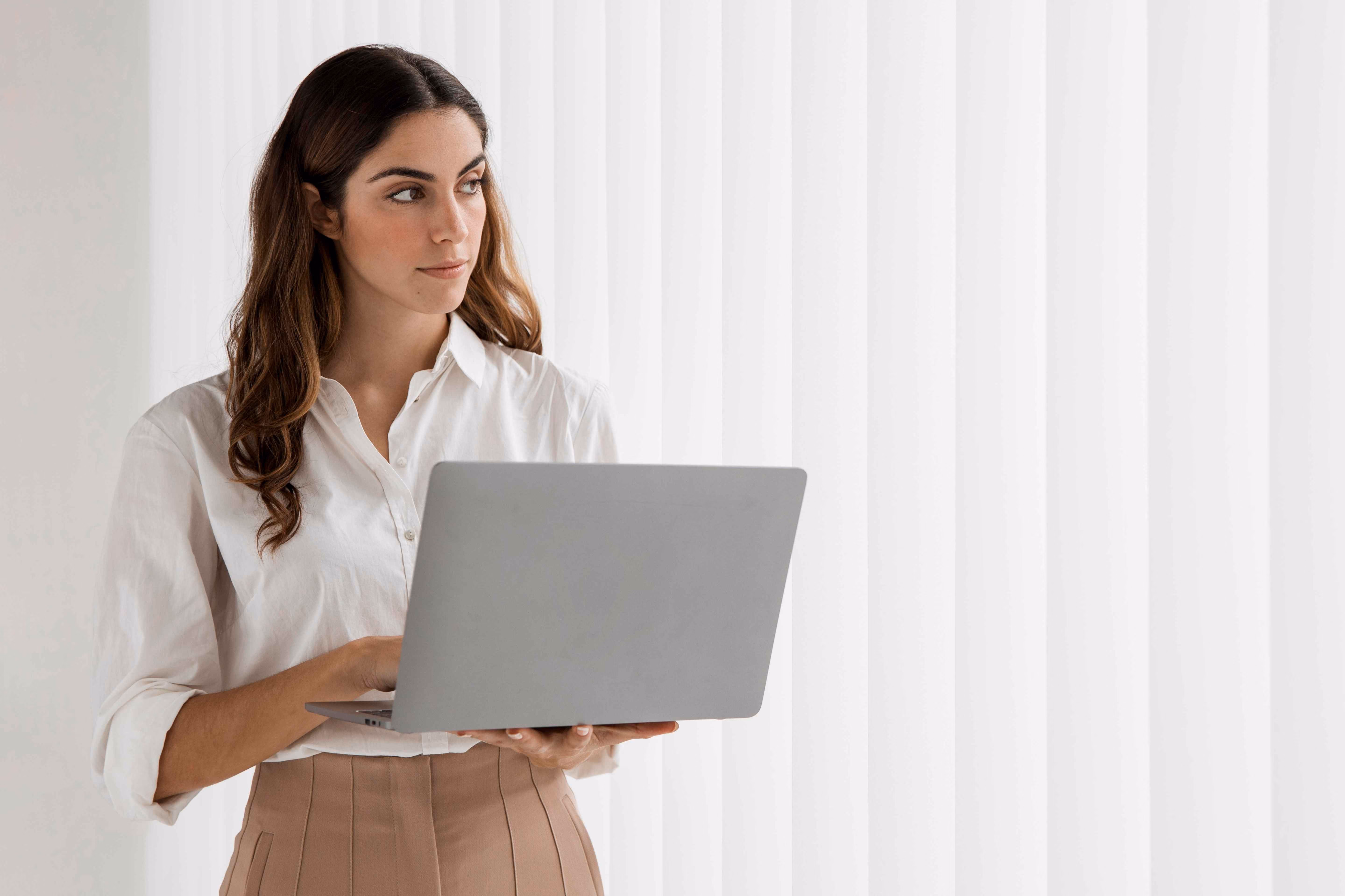 Jeune femme en chemisier blanc tenant un ordinateur portable ouvert