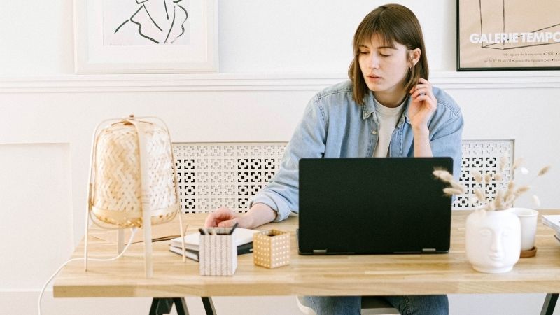 Jeune femme pensive travaillant sur un ordinateur portable à son bureau