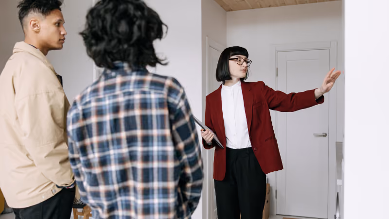 Agente immobilière faisant visiter un logement à deux jeunes hommes