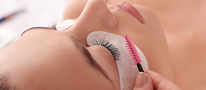Pose d'extensions de cils au goupillon sur une cliente allongée