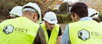Étudiants de l'ESCT en casques de chantier et gilets jaunes, de dos