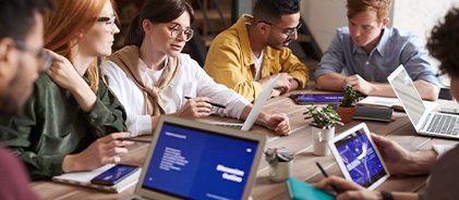 Groupe d'étudiants travaillant autour d'une table avec ordinateurs portables et tablettes