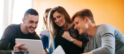 Trois jeunes étudiants souriants partageant une tablette