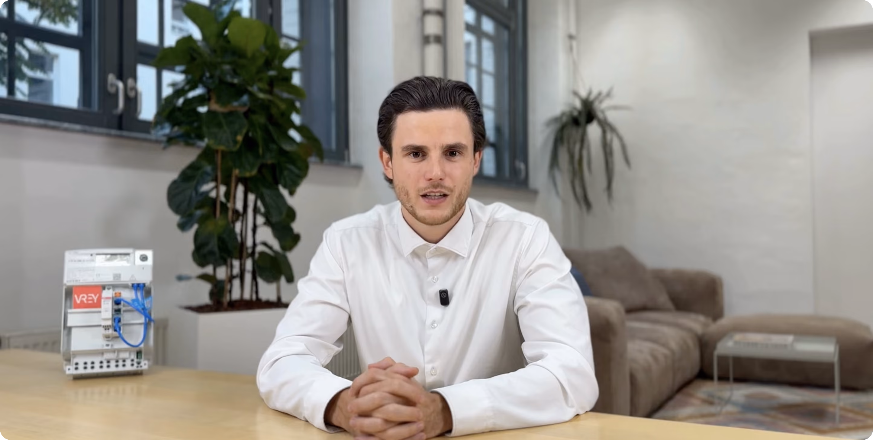 Video-Vorschau: VREY-Mitarbeiter erklärt GGV im Büro, daneben ein Smart Meter mit VREY-Logo
