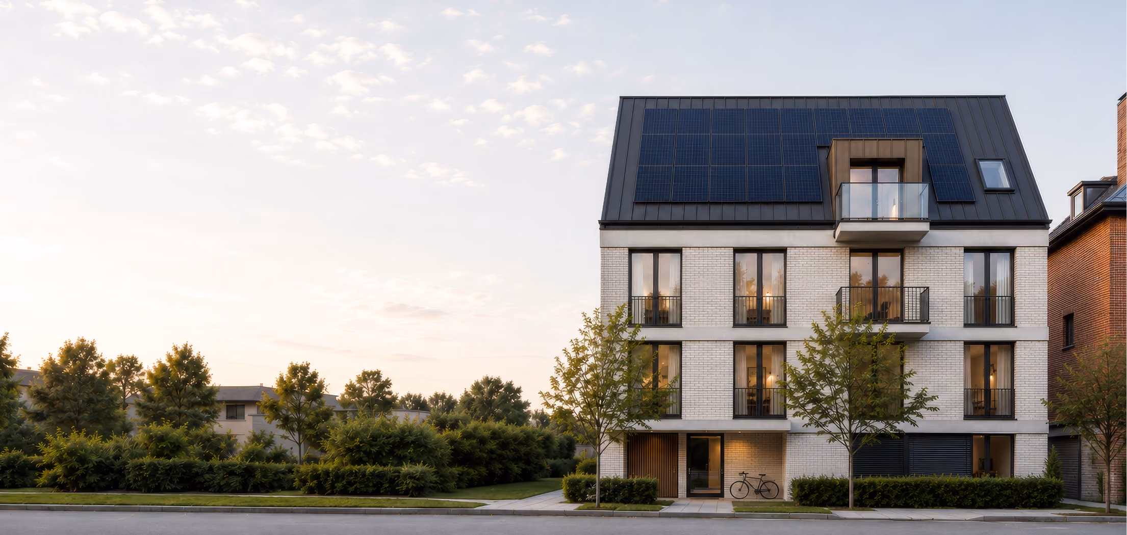 Modernes Mehrfamilienhaus mit Photovoltaikanlage auf dem Dach in der Abendsonne