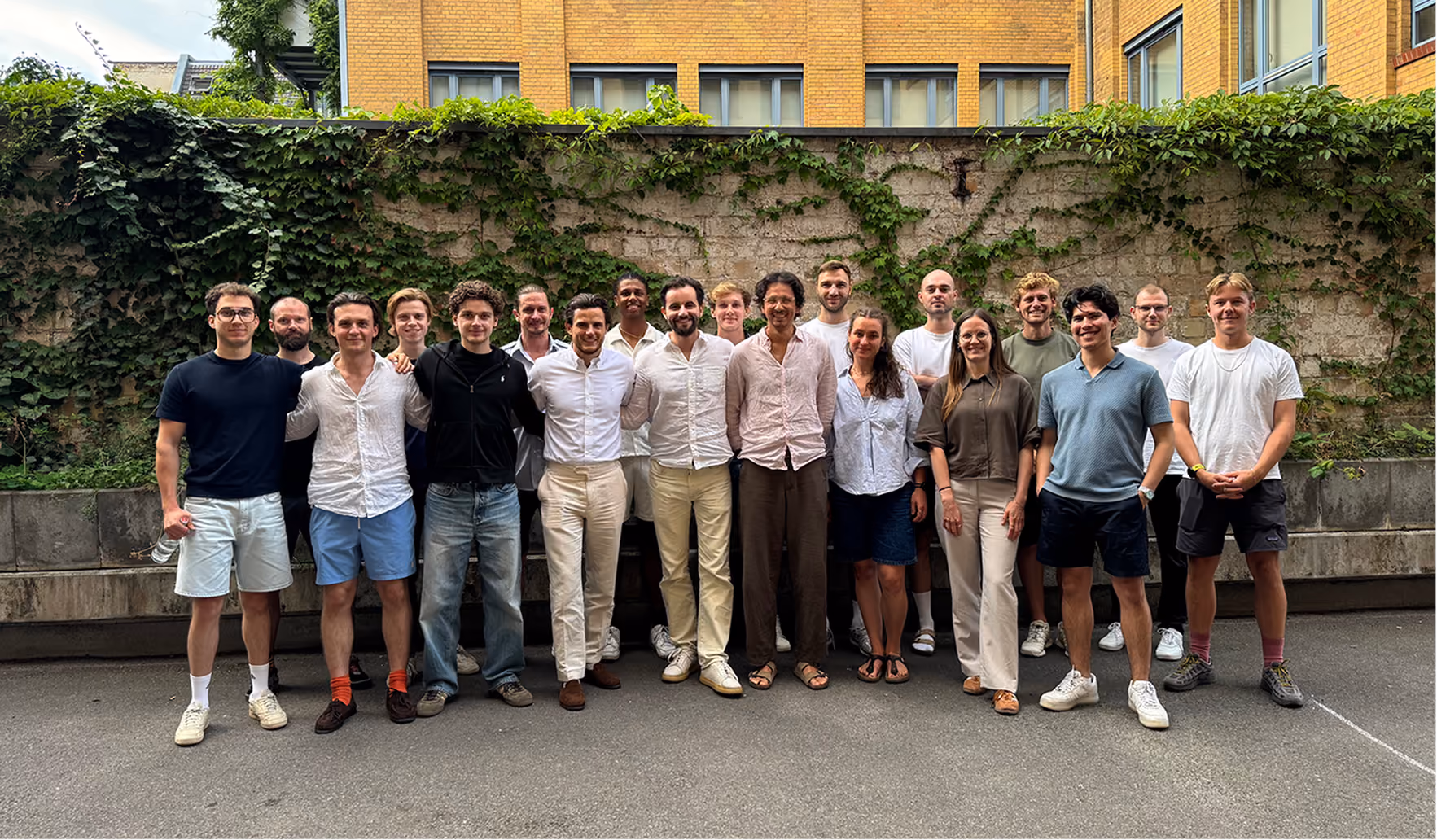 Gruppenfoto des VREY-Teams vor einer efeubewachsenen Mauer im Innenhof