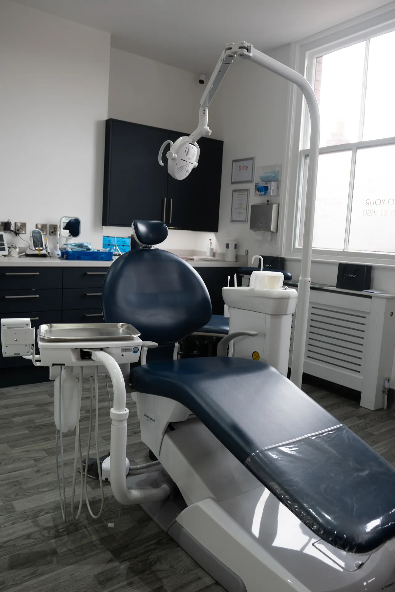 Empty dental examination chair with attached overhead light and medical equipment in a clean dental office.