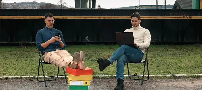 Three people working at a large desk with computers in a modern office space.