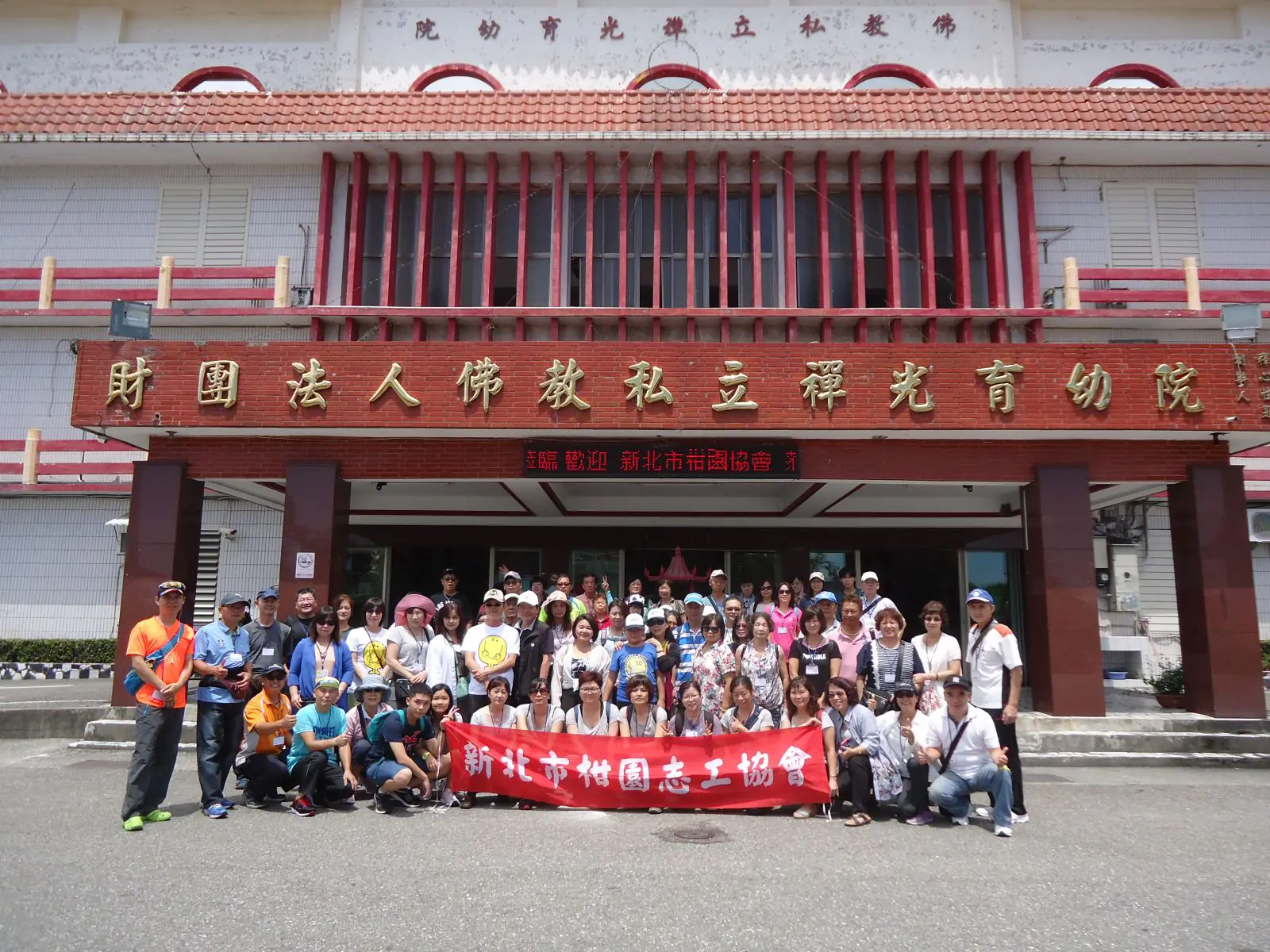 新北市柑園志工協會與禪光育幼院在院舍前合影