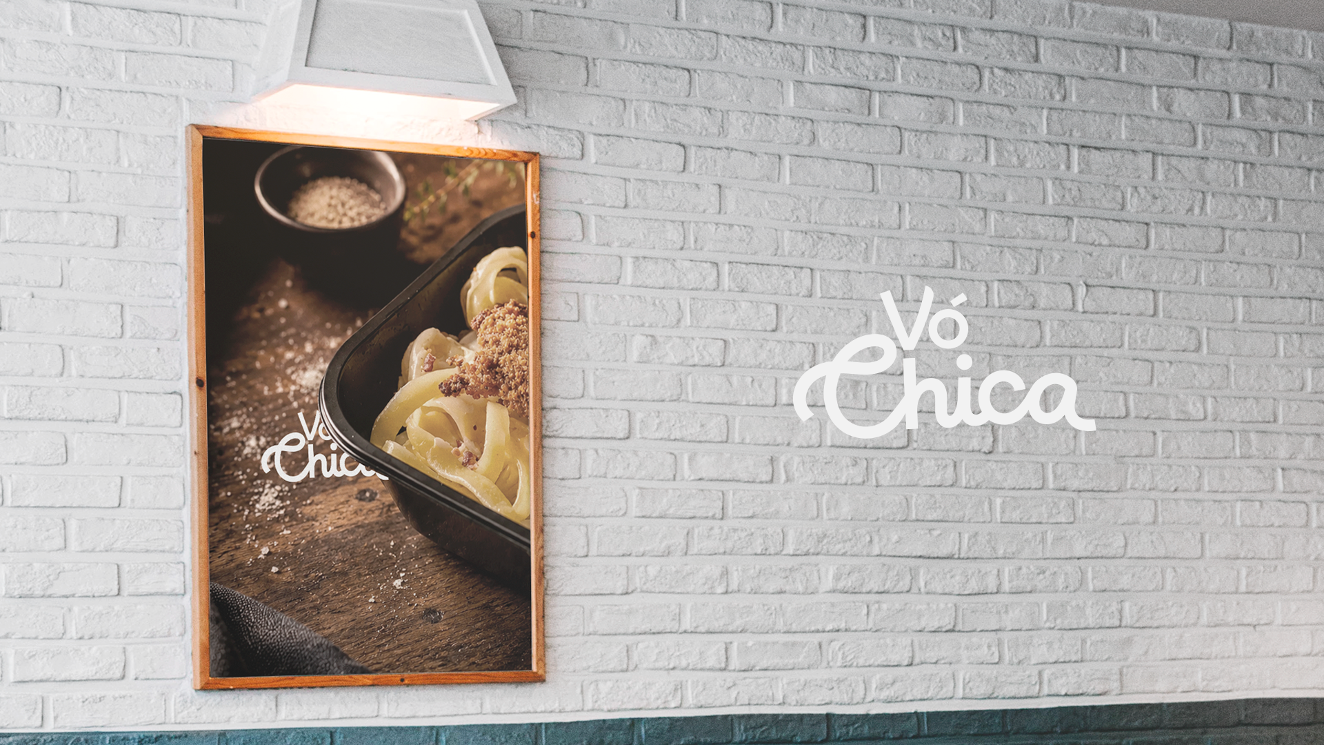 White brick wall with a lighted framed food photo and the text 'Vó Chica' on the wall.