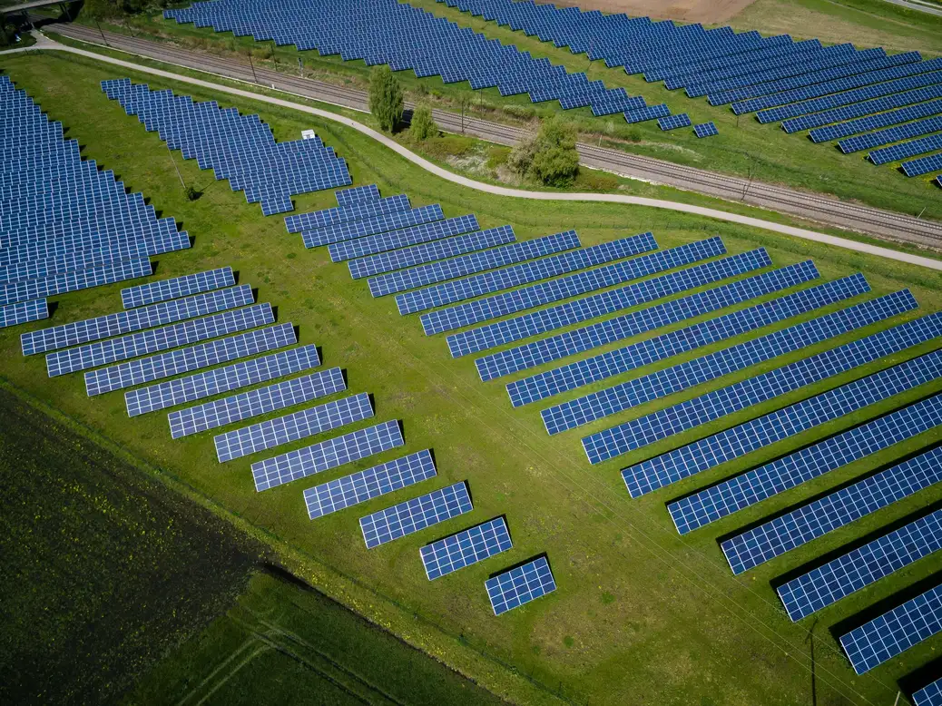 Aerial view of a solar farm with rows of solar panels installed on grassland.