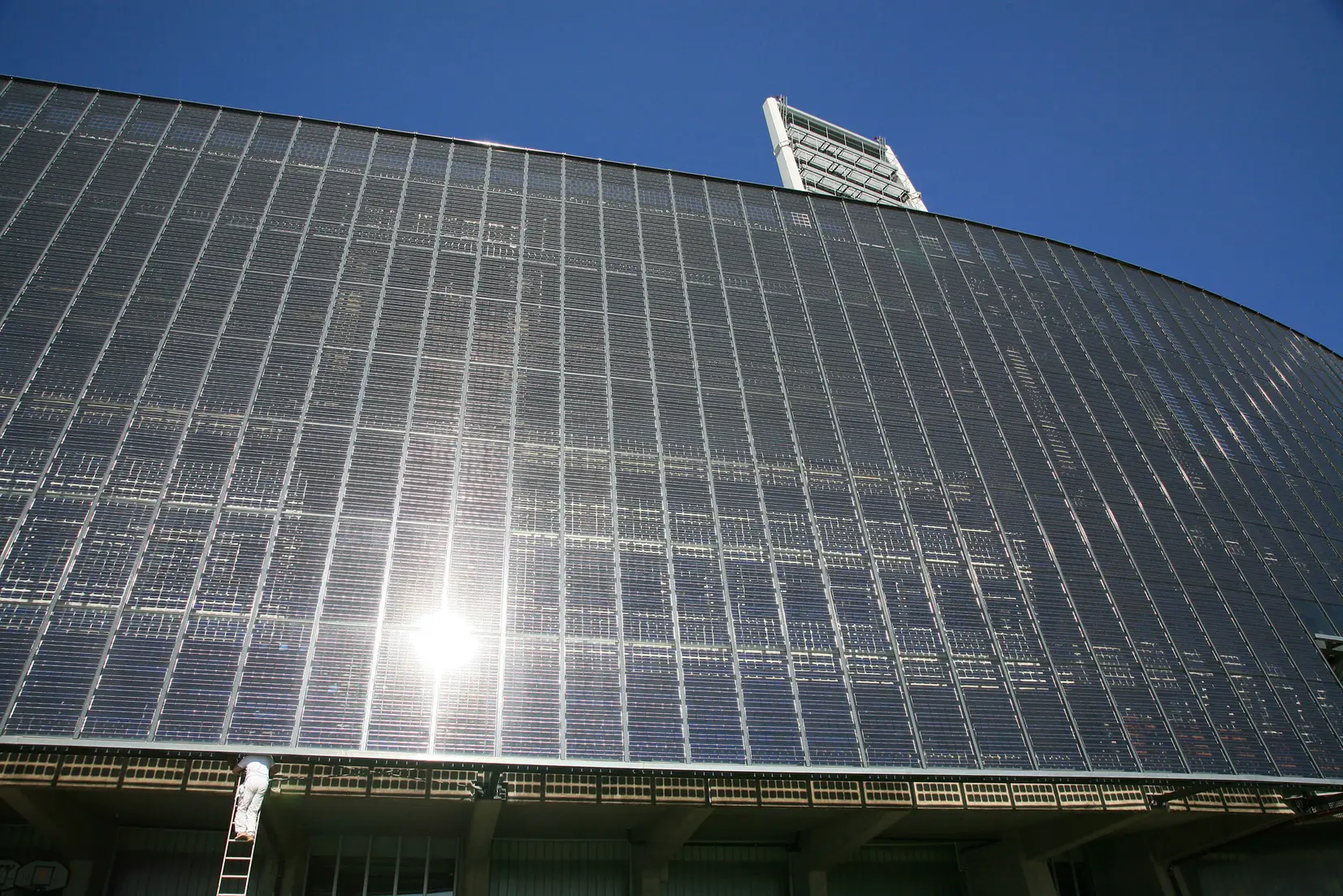 Large solar panel installation covering the side of a building, with sunlight reflecting off the panels